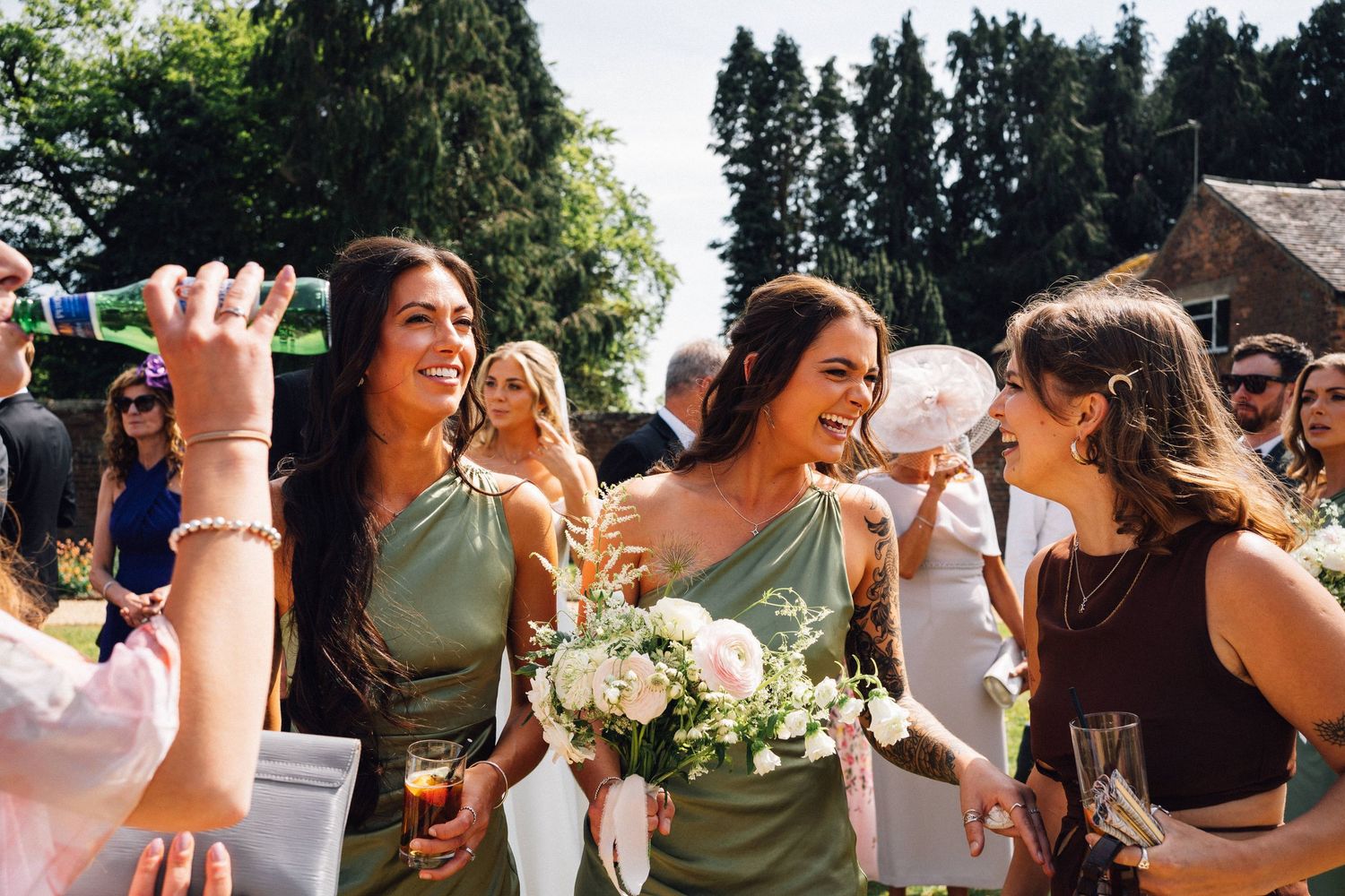 Wedding guests celebrating and raising glasses during an outdoor summer reception.