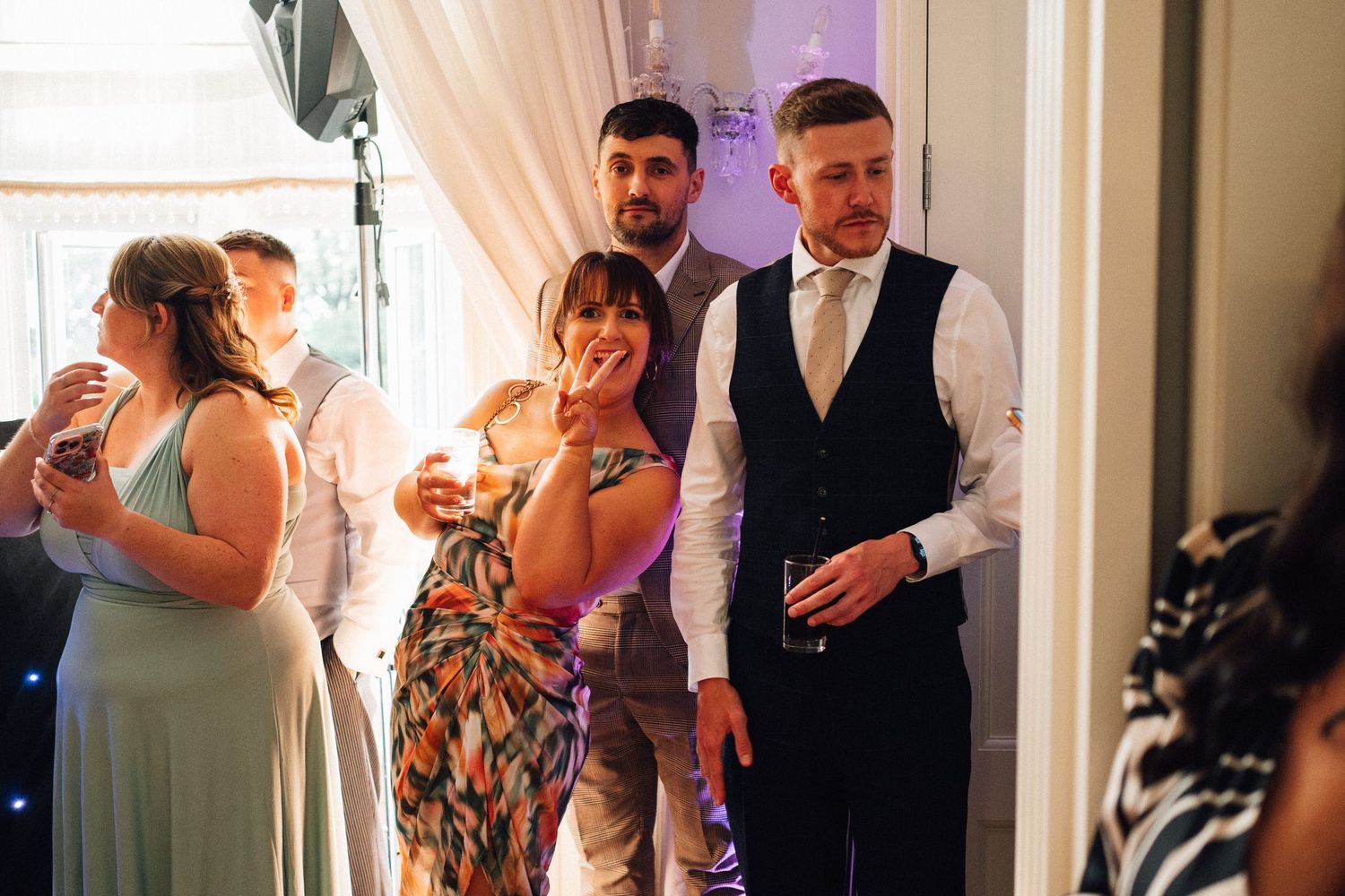 Wedding reception guests dancing and mingling in an elegant venue with soft lighting.