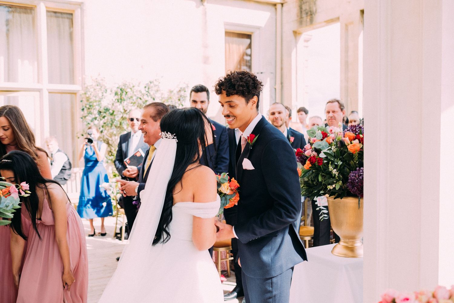 Wedding celebration scene in an elegant bright indoor venue with floral decorations.