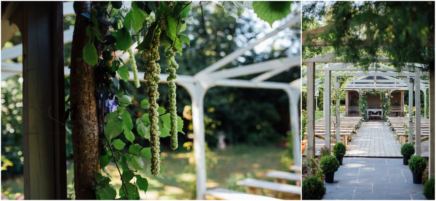 Garden wedding venue walkway framed by white pergolas and lush greenery.