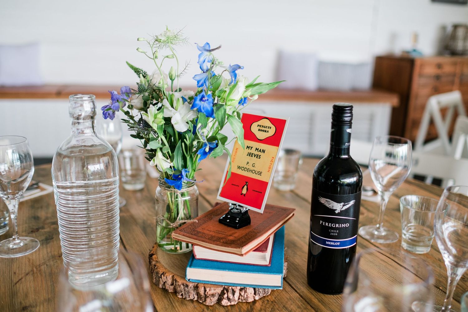 Wedding reception table setup with blue flowers and wine bottles as decorations.