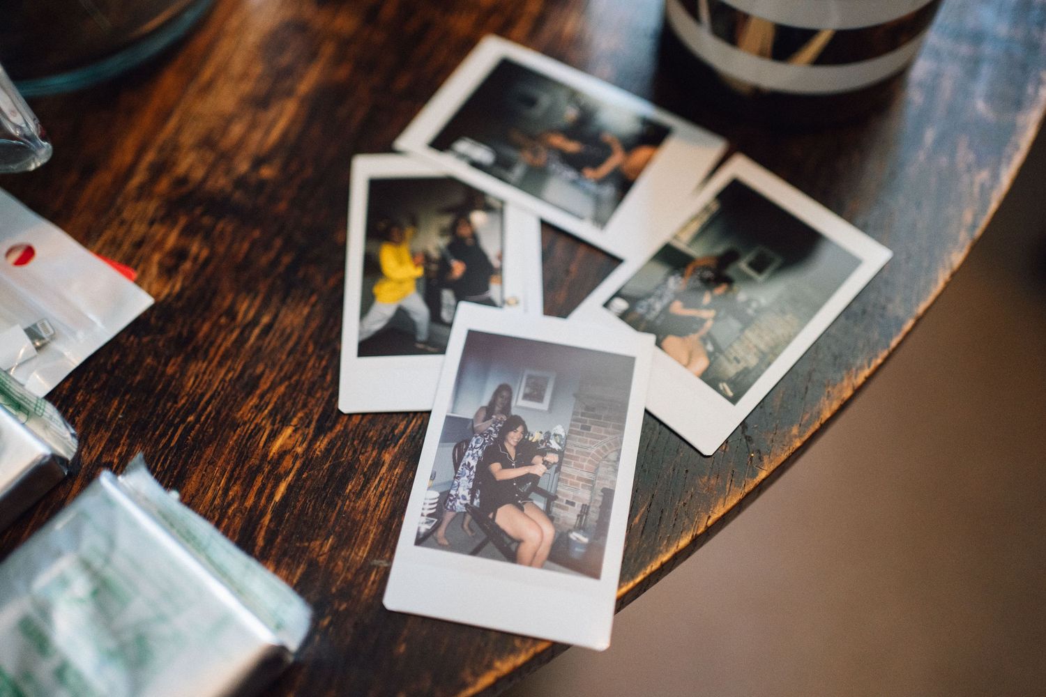 Collection of polaroid wedding photos scattered on dark wooden surface.