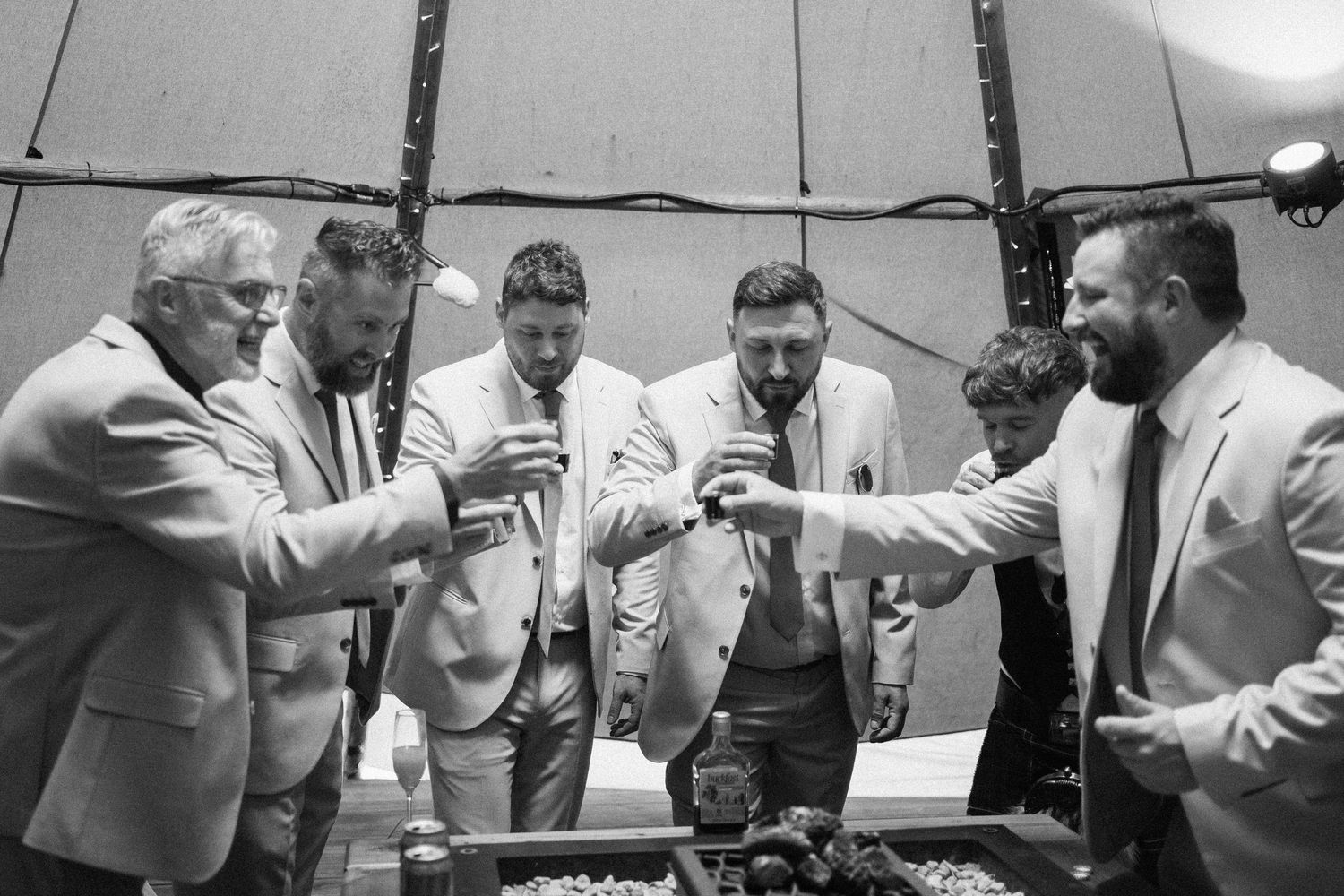 Group gathered around table inside white tent for drinks.
