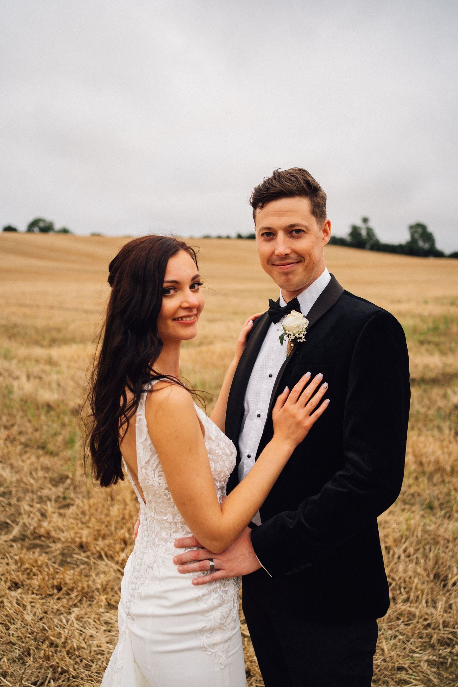 Romantic couple portraits in formal attire against a scenic wheat field backdrop.