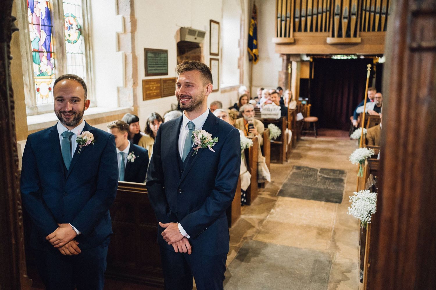 Church interior with wooden pews and organ pipes during wedding ceremony.
