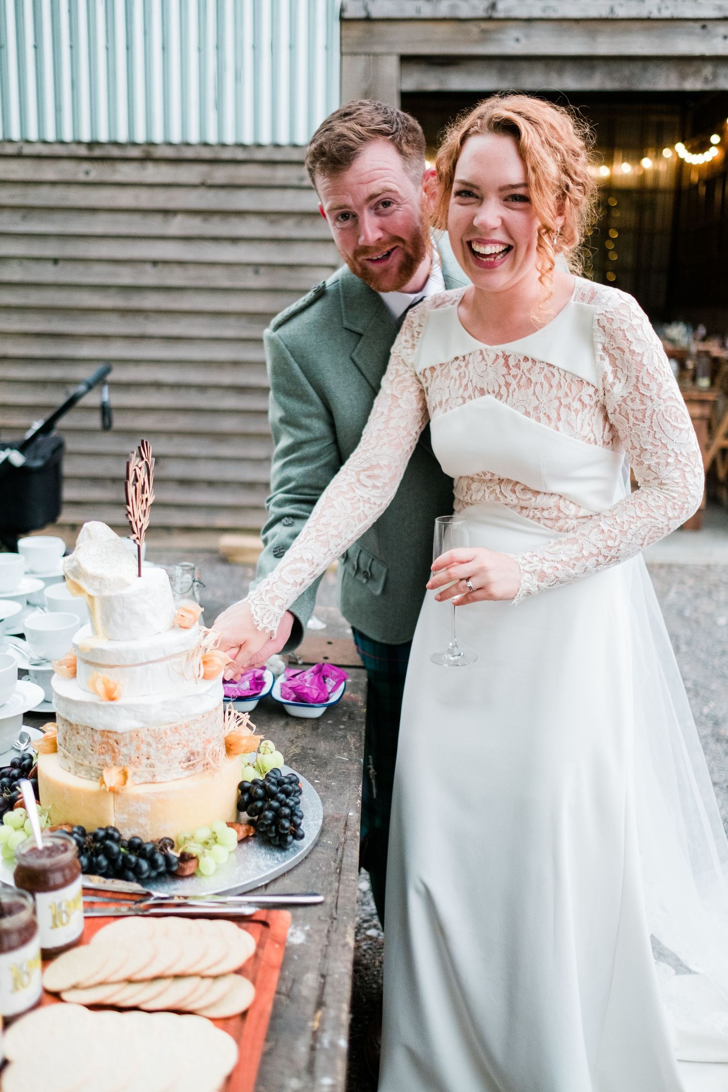 Couple cuts their wedding cake at a rustic barn reception while sharing a joyful moment together.