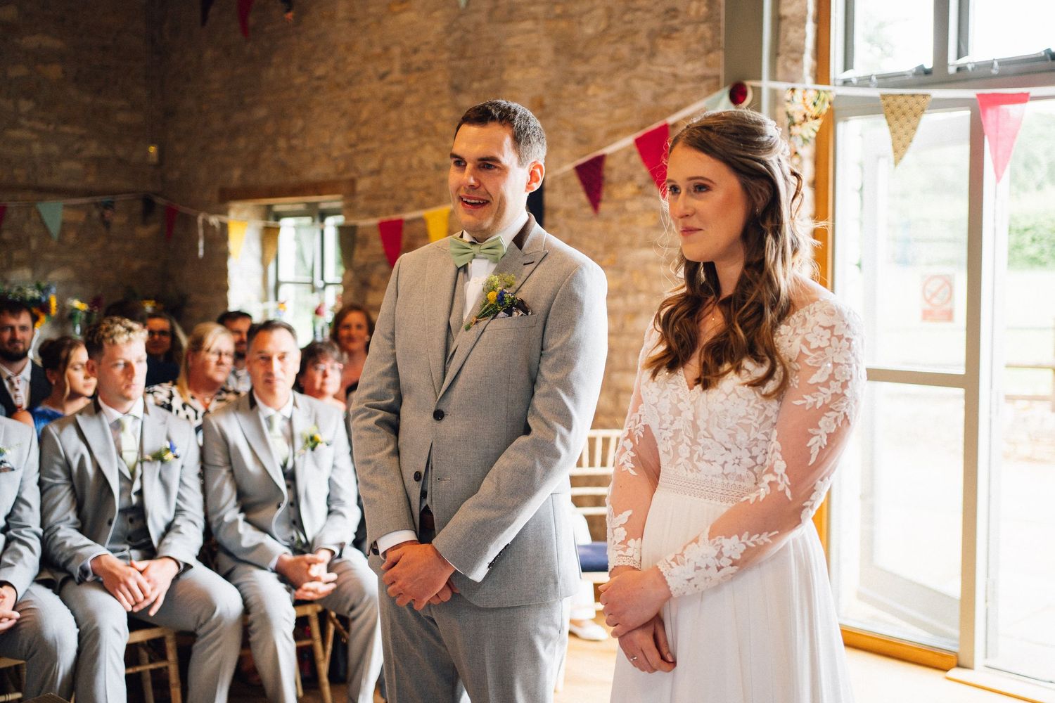 A wedding ceremony in progress inside a rustic brick venue with natural lighting.