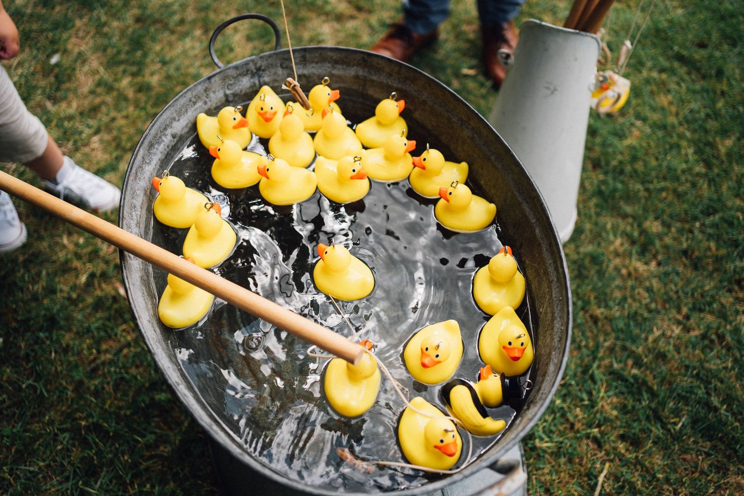 Yellow rubber ducks floating in an ice bucket filled with champagne bottles at an outdoor party setting.