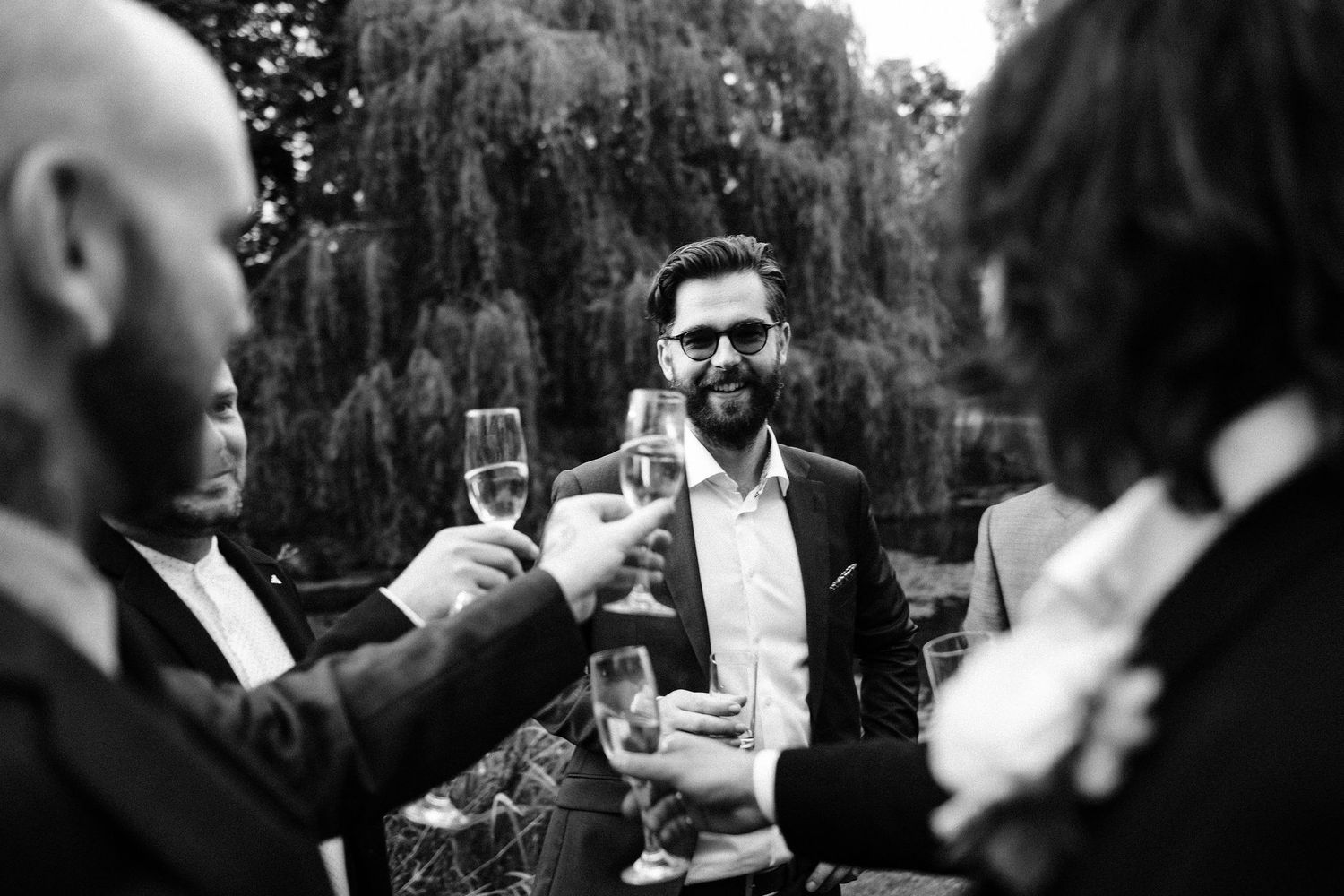 Wedding guests enjoy champagne toasts during an outdoor celebration at dusk.