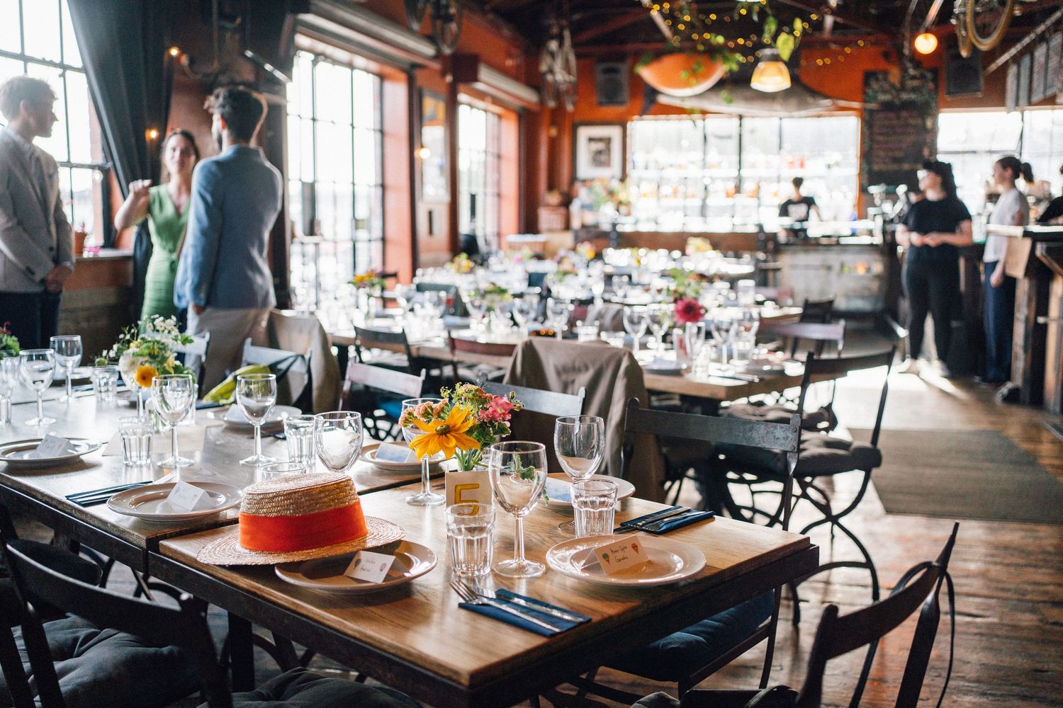 Wedding reception venue with elegant table settings and large windows.
