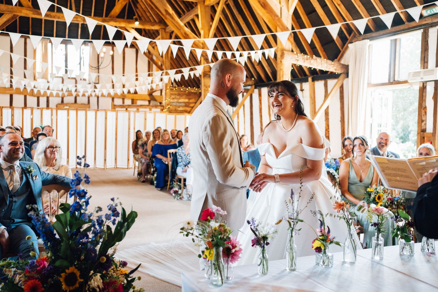 Rustic barn wedding venue decorated with white bunting and string lights during a celebration.