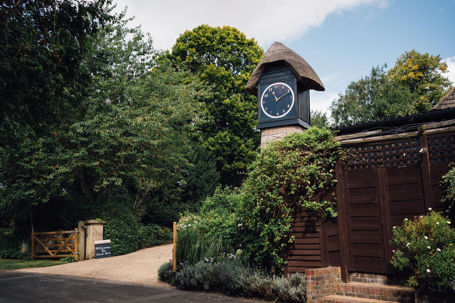 A scenic garden pathway leads through wooden fences and lush greenery on a sunny day.