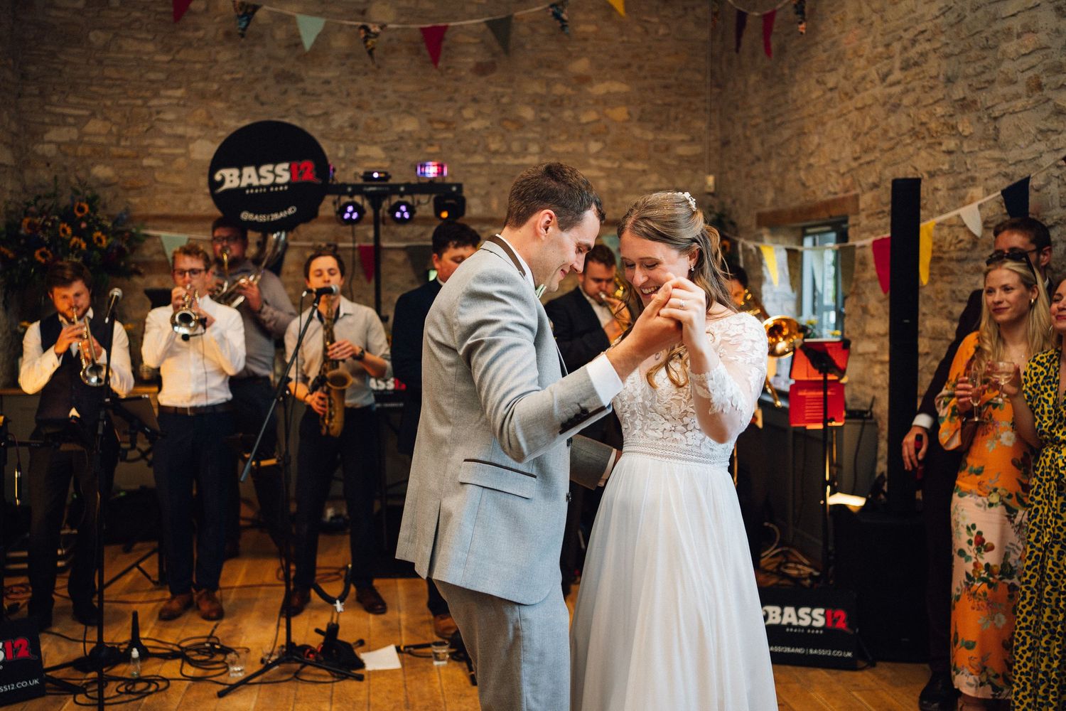 Wedding reception dance floor with colorful bunting decorations and stone wall backdrop.