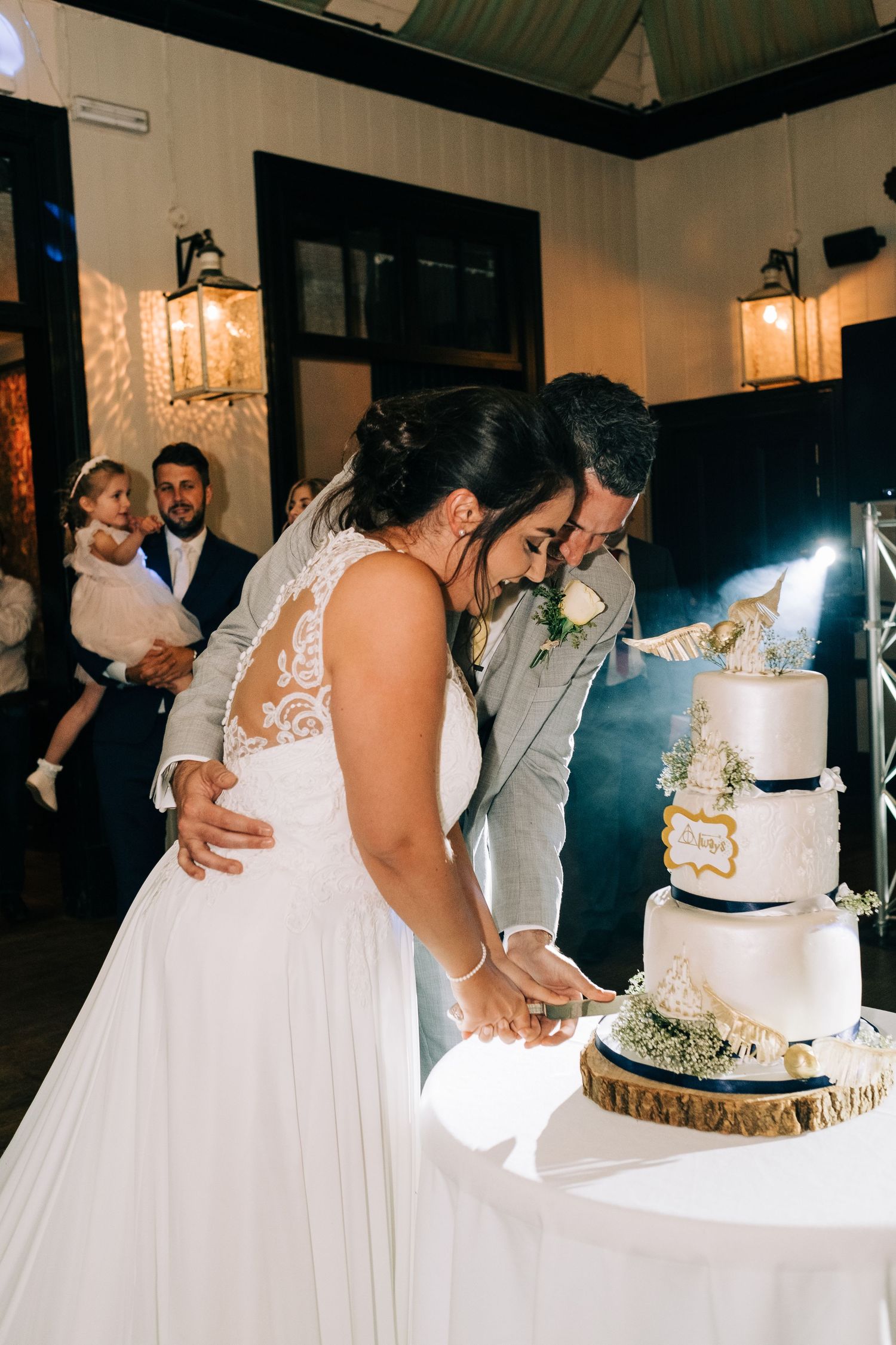 Wedding celebration scene with elegant cake display and guests gathering around.