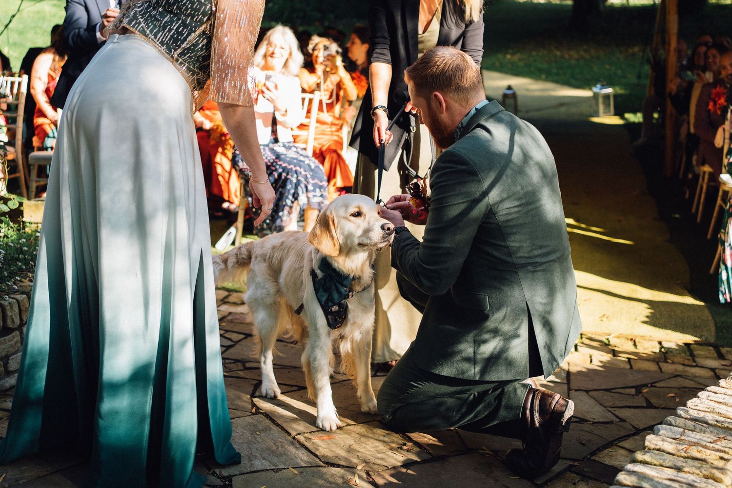 Wedding ceremony guests seated outdoors under string lights during golden hour.