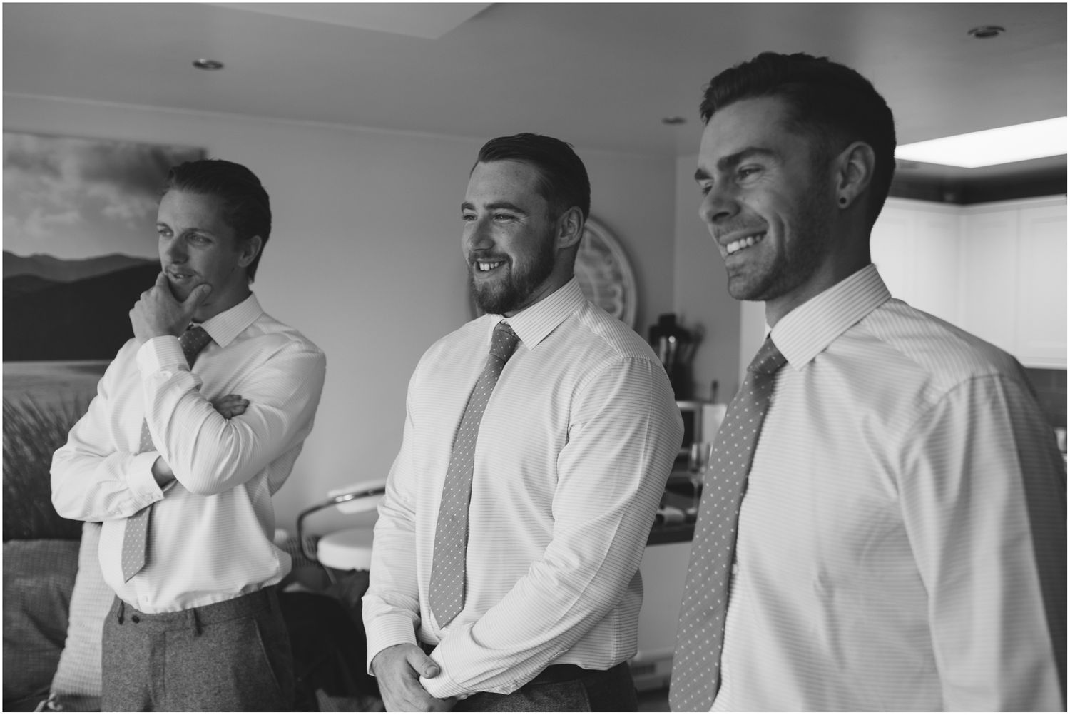 Three people in white dress shirts and ties share a lighthearted moment together.