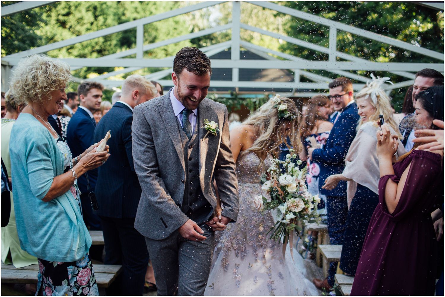 Outdoor wedding celebration with guests mingling under white pergola.