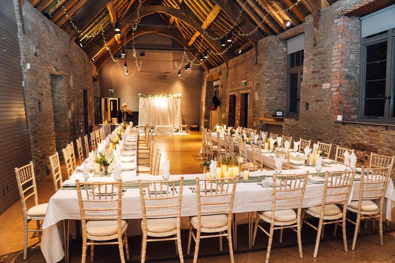 Rustic barn wedding reception venue with white chairs and exposed brick walls.
