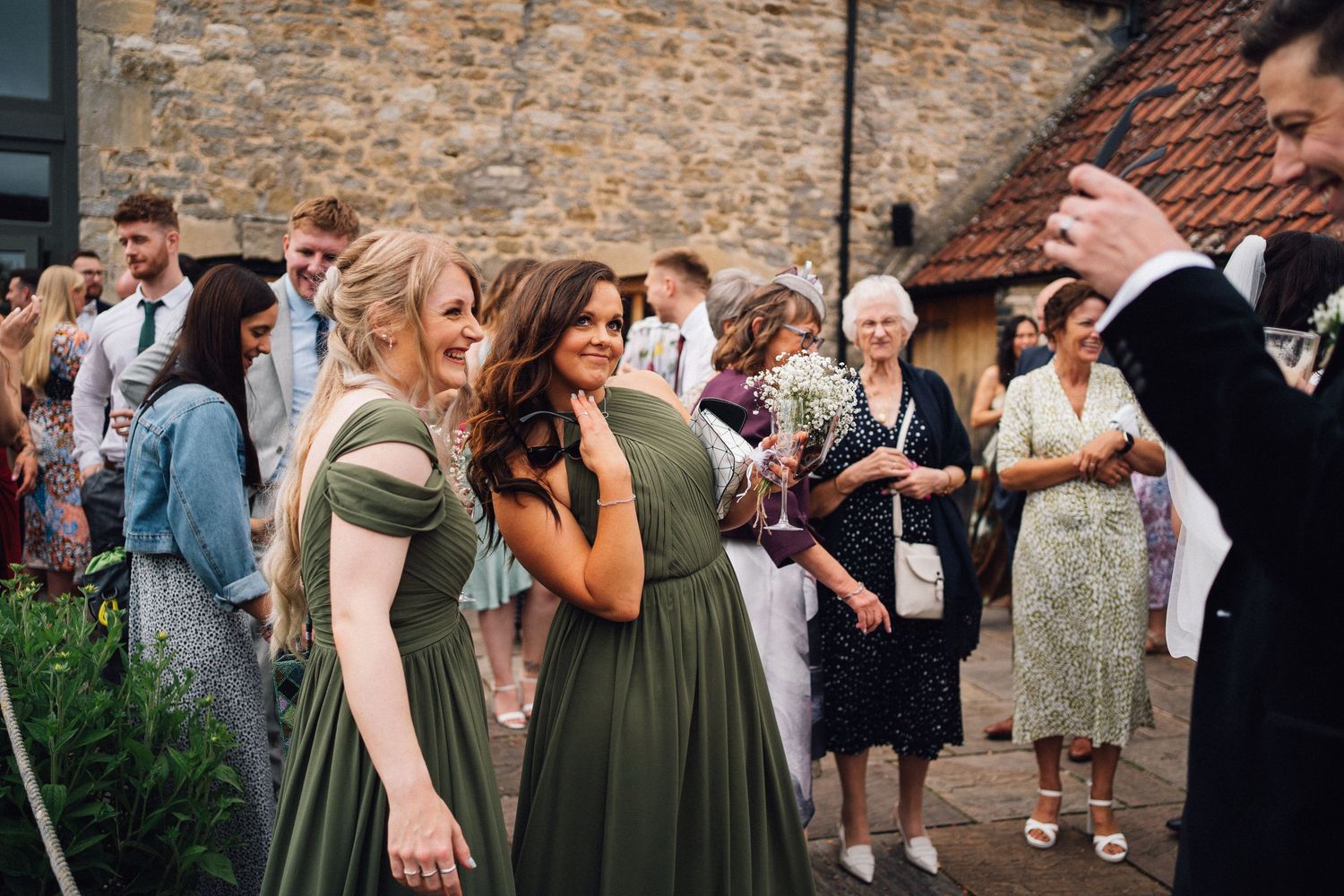Wedding party gathers outside a historic stone building during an outdoor celebration.