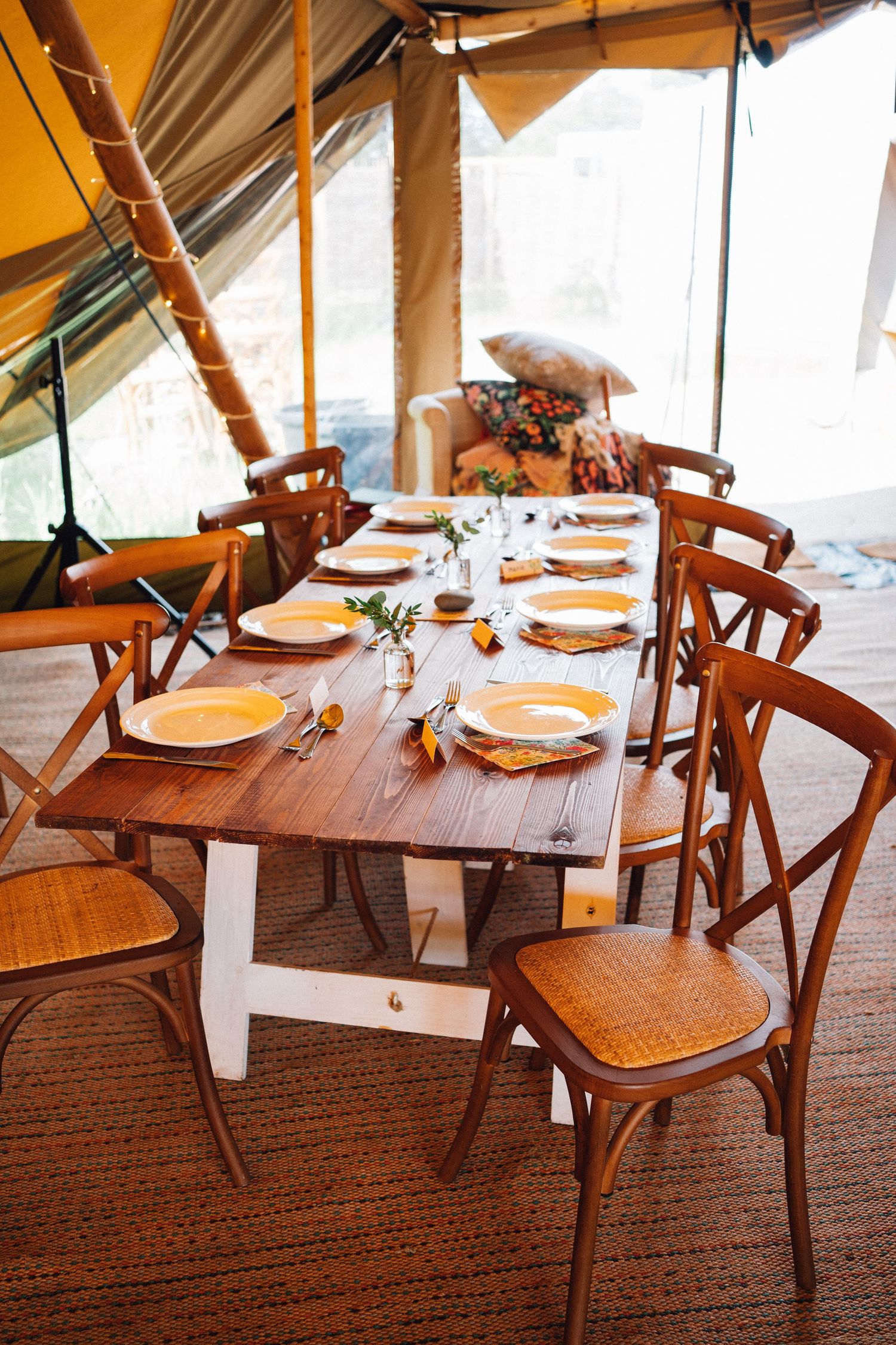 Wooden dining table set with place settings and cane-back chairs on a patterned carpet.