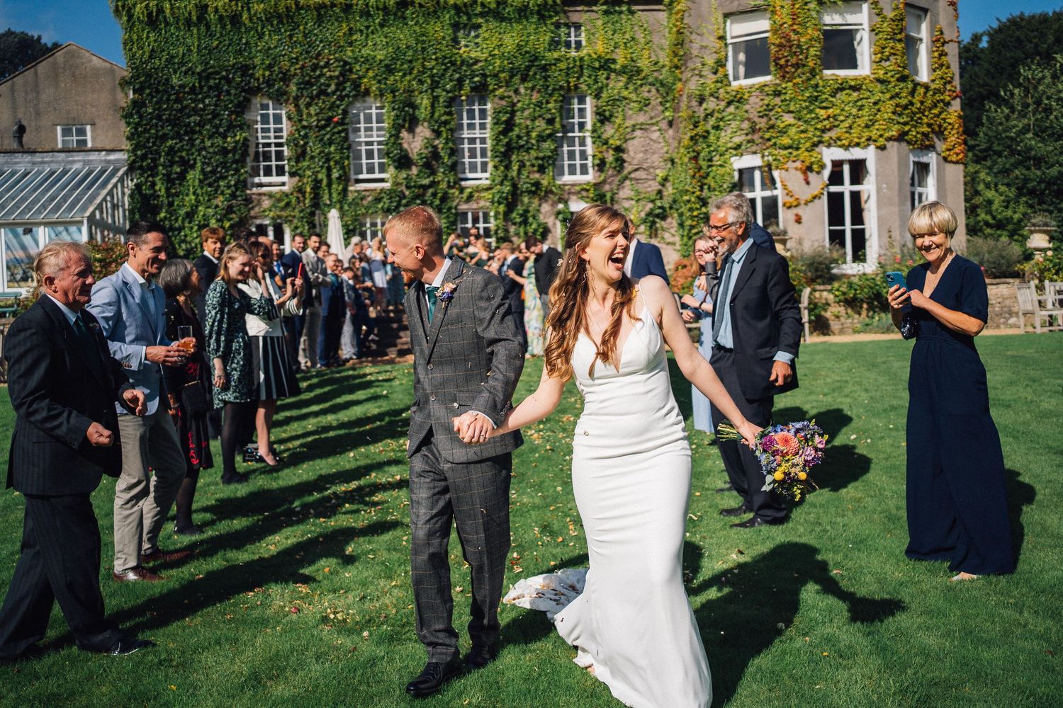 Wedding celebration on manicured lawn with guests gathered around.