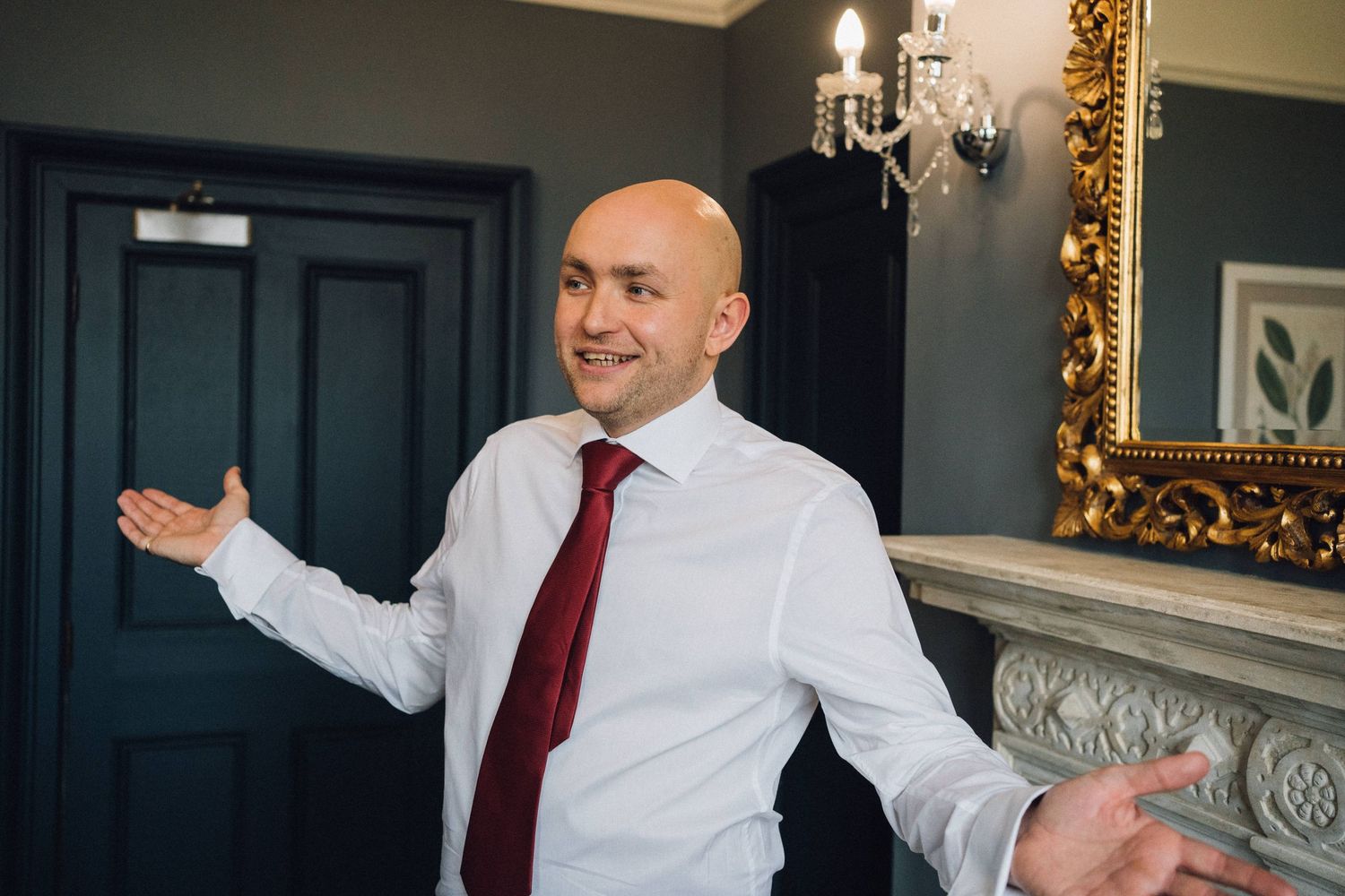 Groomsmen sharing lighthearted moments in an elegantly decorated room with gold-framed mirrors.