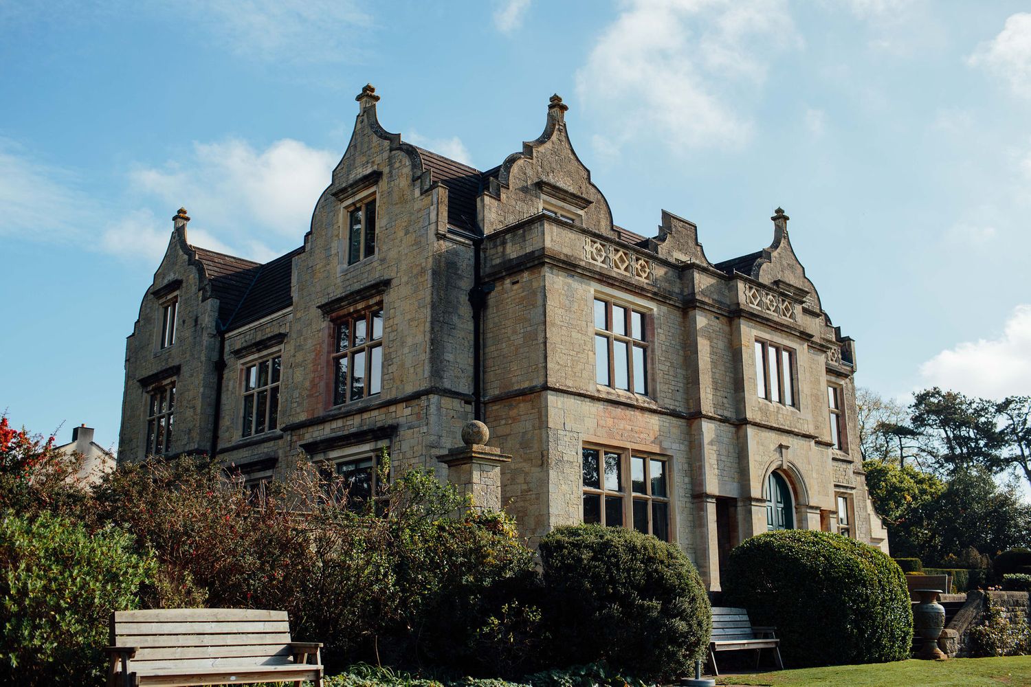 Panoramic view of a grand stone manor house with Gothic architectural features.