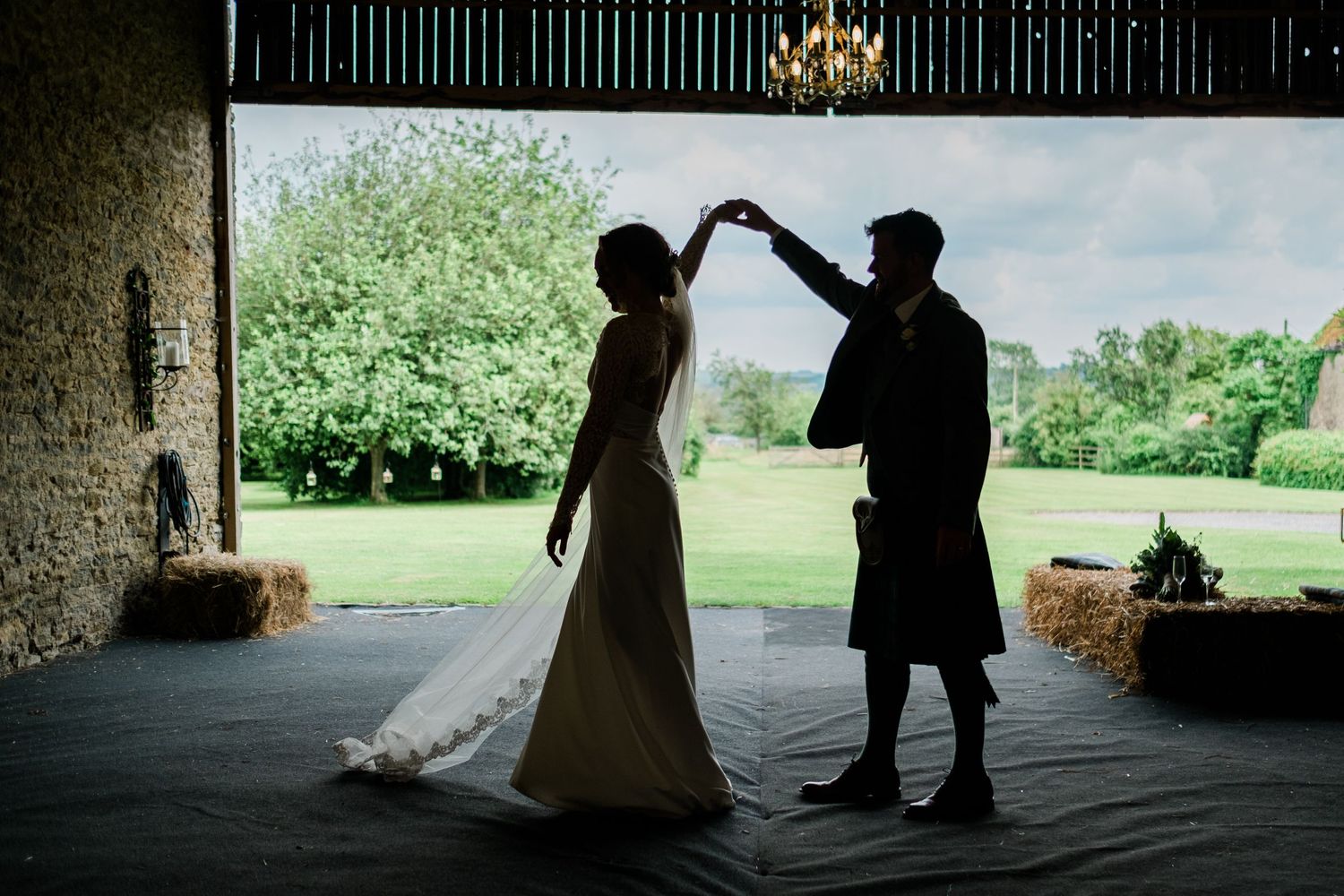 A silhouetted couple dancing together under covered outdoor area.