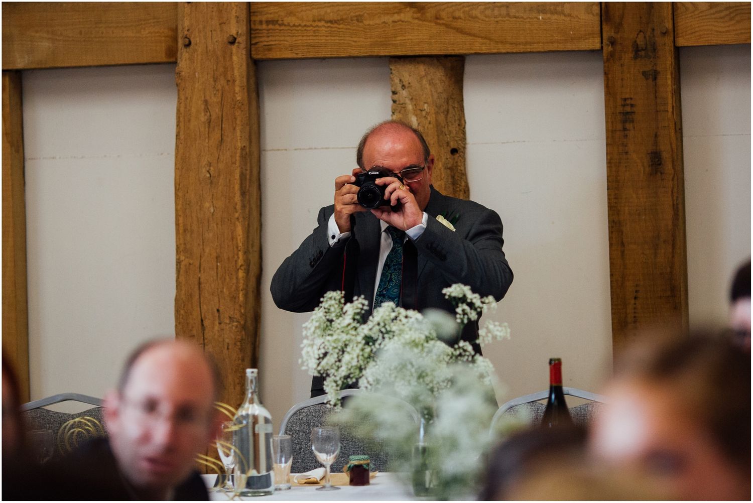 Wedding reception candid moments captured through wooden beams.