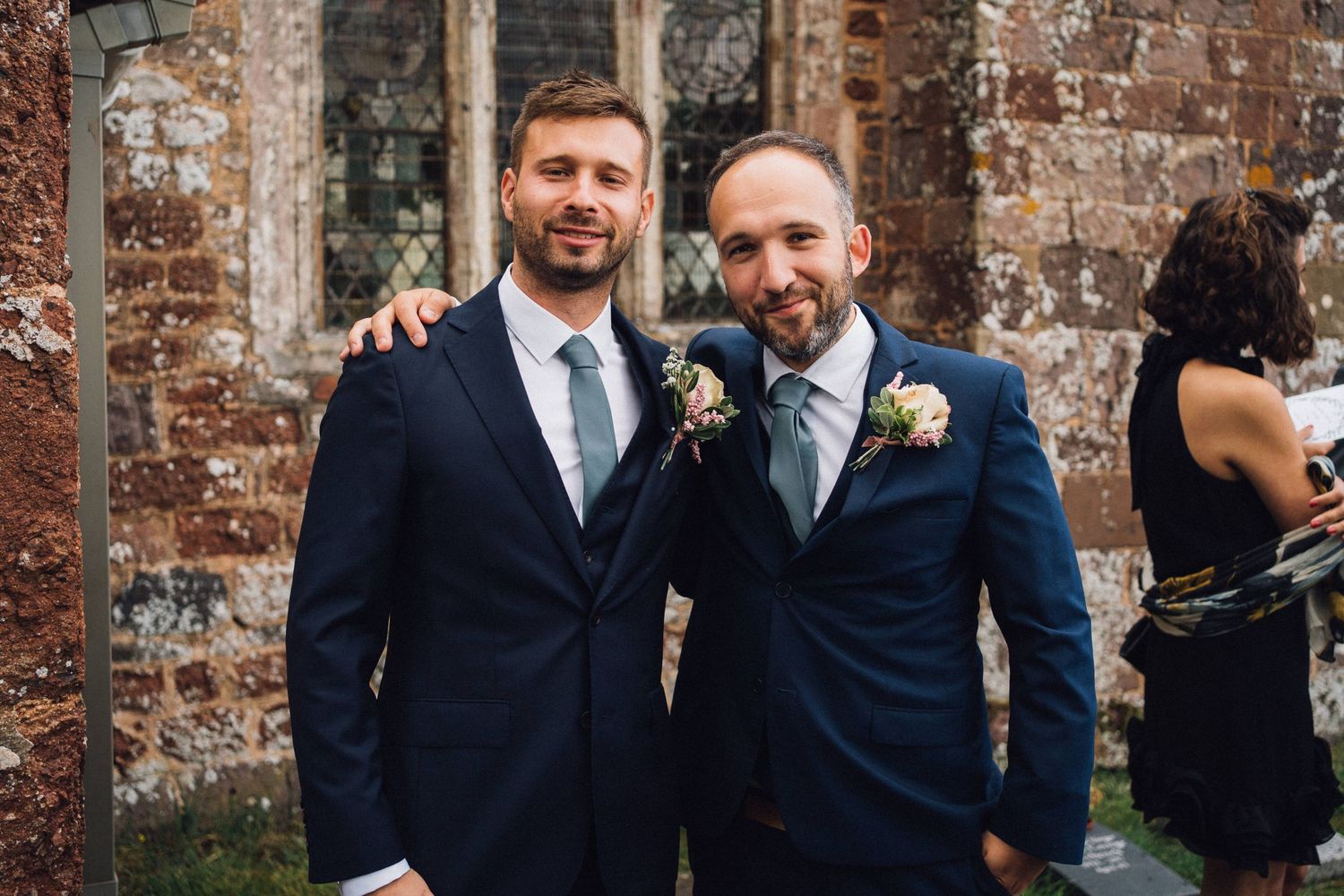 Wedding party gathered outside historic brick church walls.