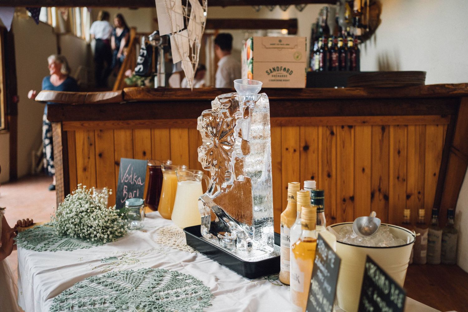 Rustic wedding bar setup with wooden decor and white floral arrangements.