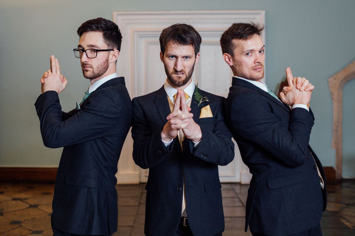 Groomsmen in navy suits striking playful poses together at a wedding.