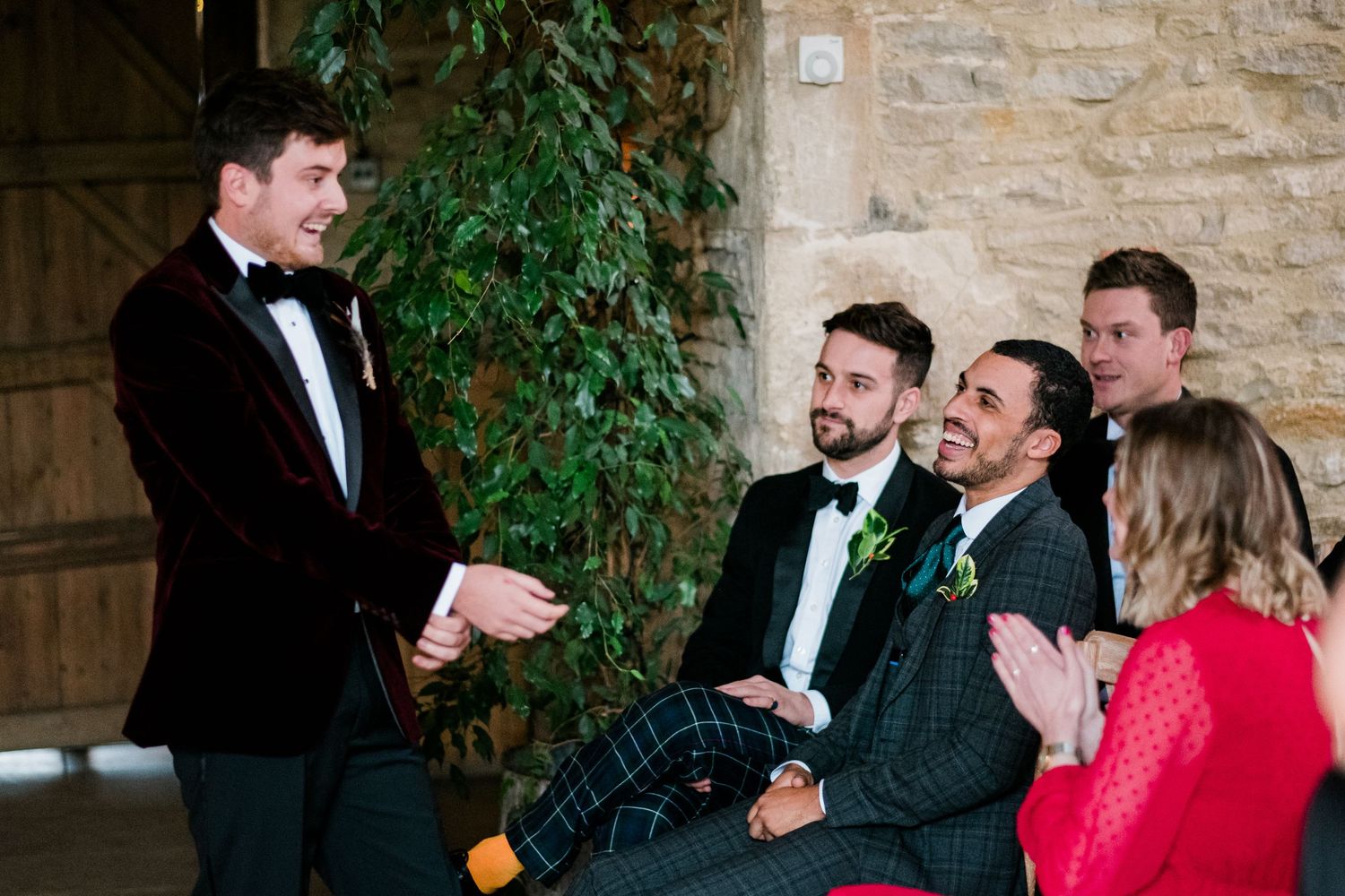 Group of formally dressed guests enjoying a celebratory moment at a stone-walled venue.