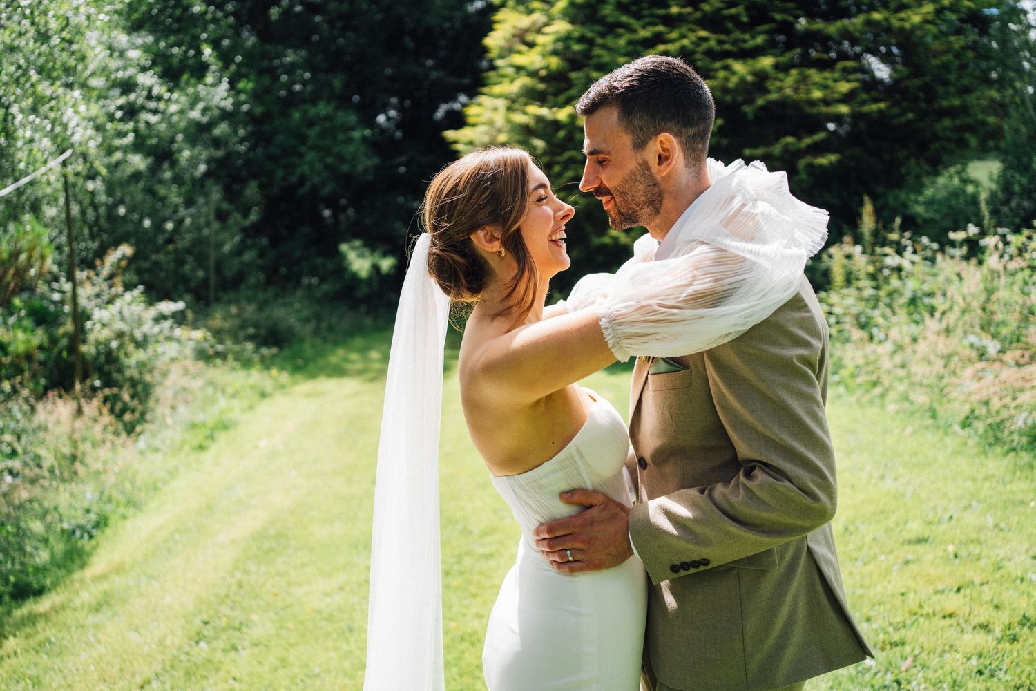Romantic garden celebration with couples embracing against lush summer greenery.