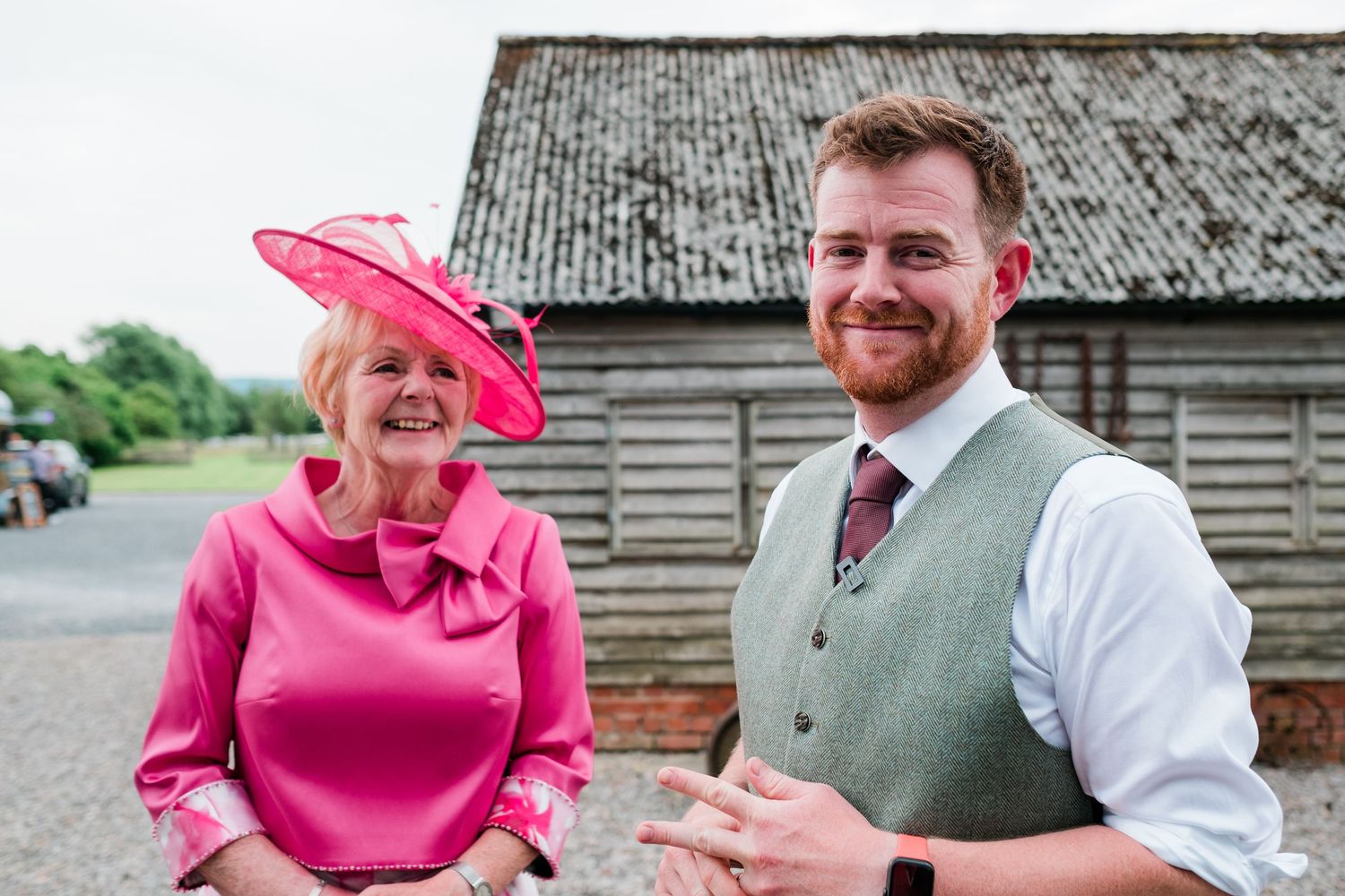 Guests in formal attire mingle outside a rustic barn during a wedding reception.