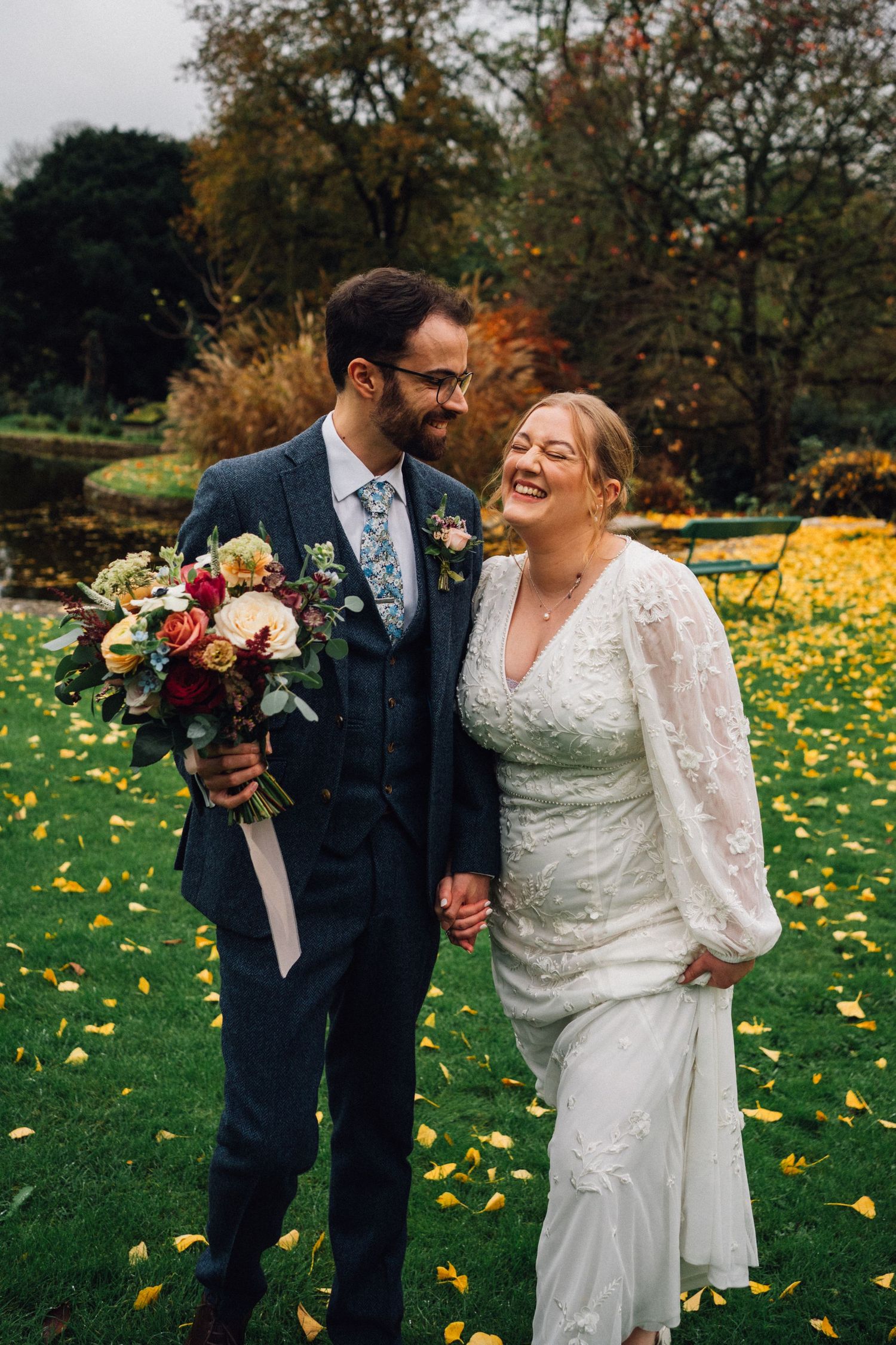 Couple shares joyful moments in autumn garden with yellow dandelions scattered across green grass.