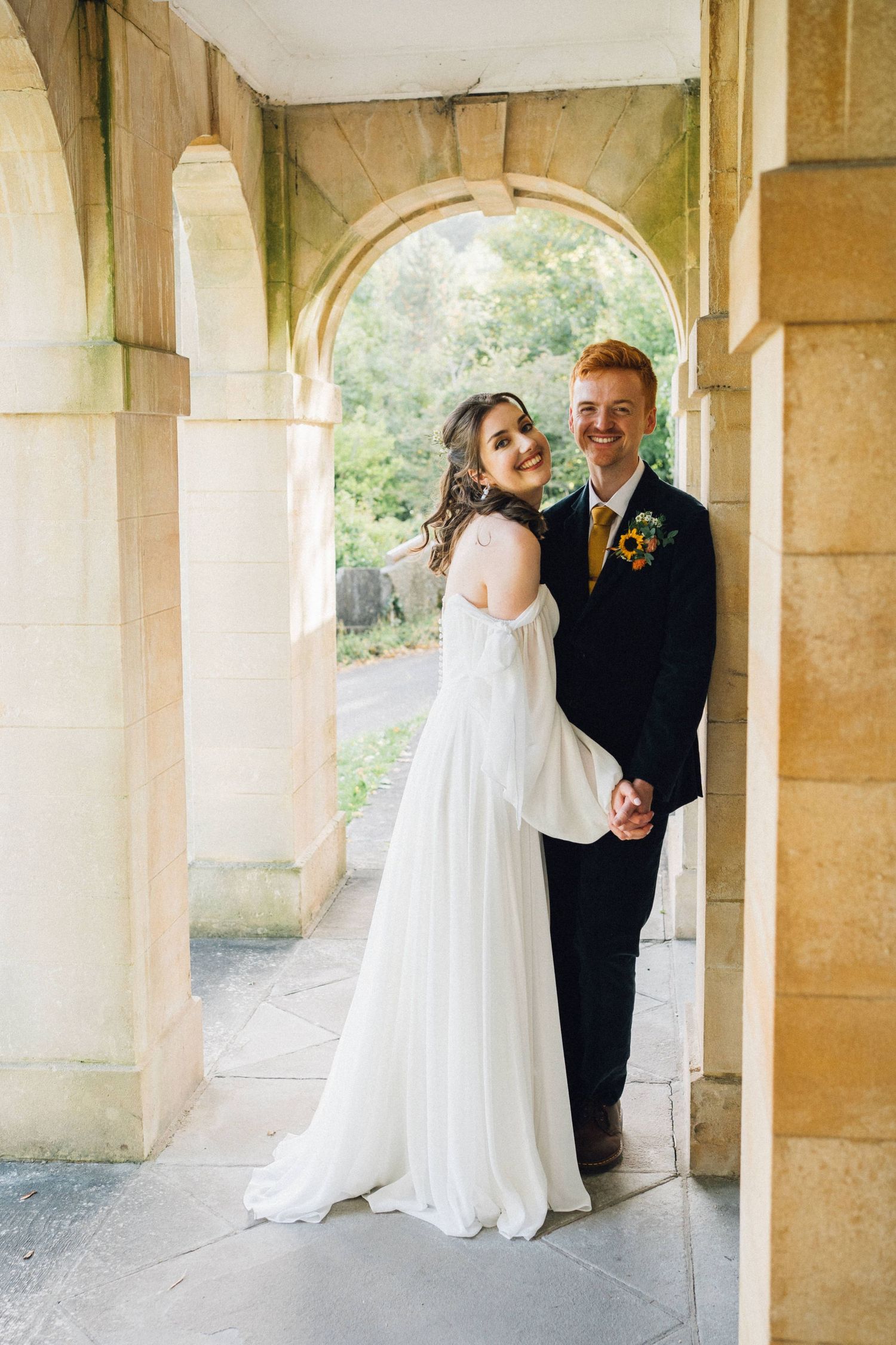 A wedding couple embraces in a series of photos taken along an elegant stone archway.