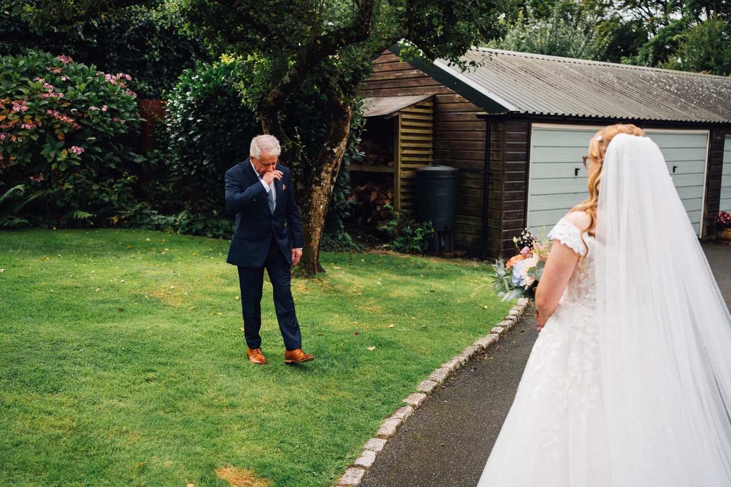 A wedding couple and child play a playful game of chase on a garden path during an outdoor celebration.