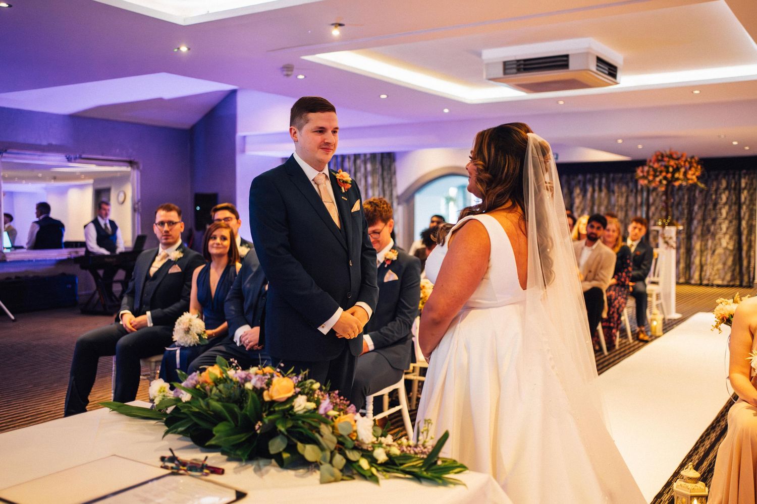 A wedding ceremony montage showing various moments including decorations, dancing, and celebration in purple-lit venue.