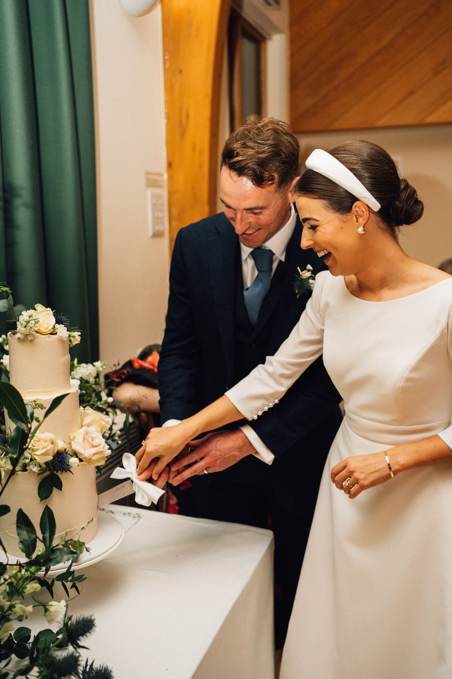 Couple signing wedding documents with white flowers and green curtains in the background.