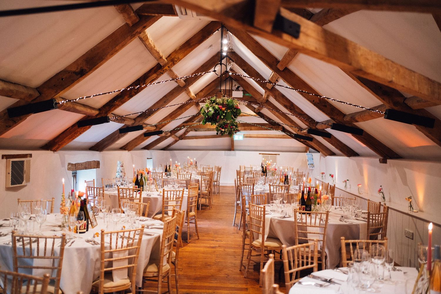 Rustic barn wedding venue with exposed wooden beams and elegant white chair setup.