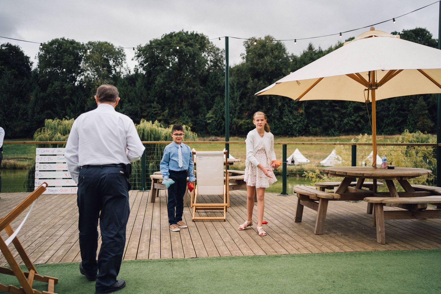 Outdoor deck area with umbrella and picnic tables set up for a gathering.