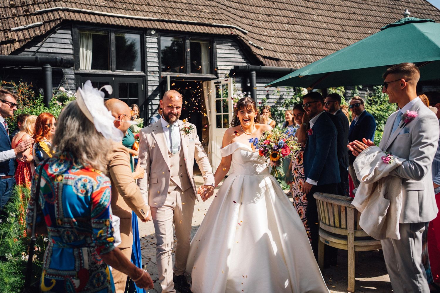Wedding celebration in a garden setting with guests mingling under a green canopy.