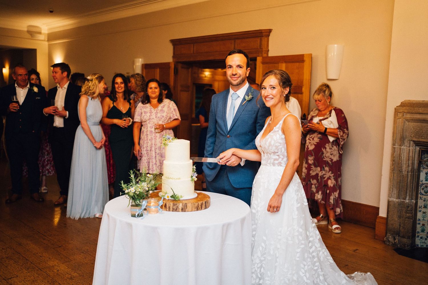 Wedding reception celebration with guests enjoying dinner and speeches in warm-lit banquet room.
