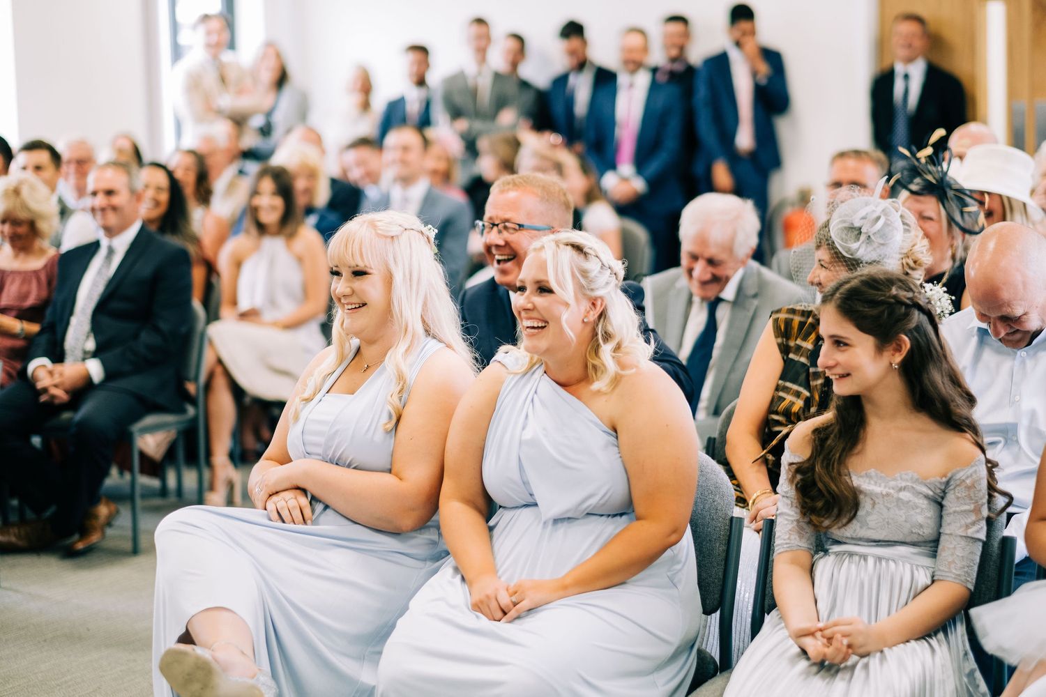 Wedding guests in formal attire seated and watching the ceremony with emotional expressions.