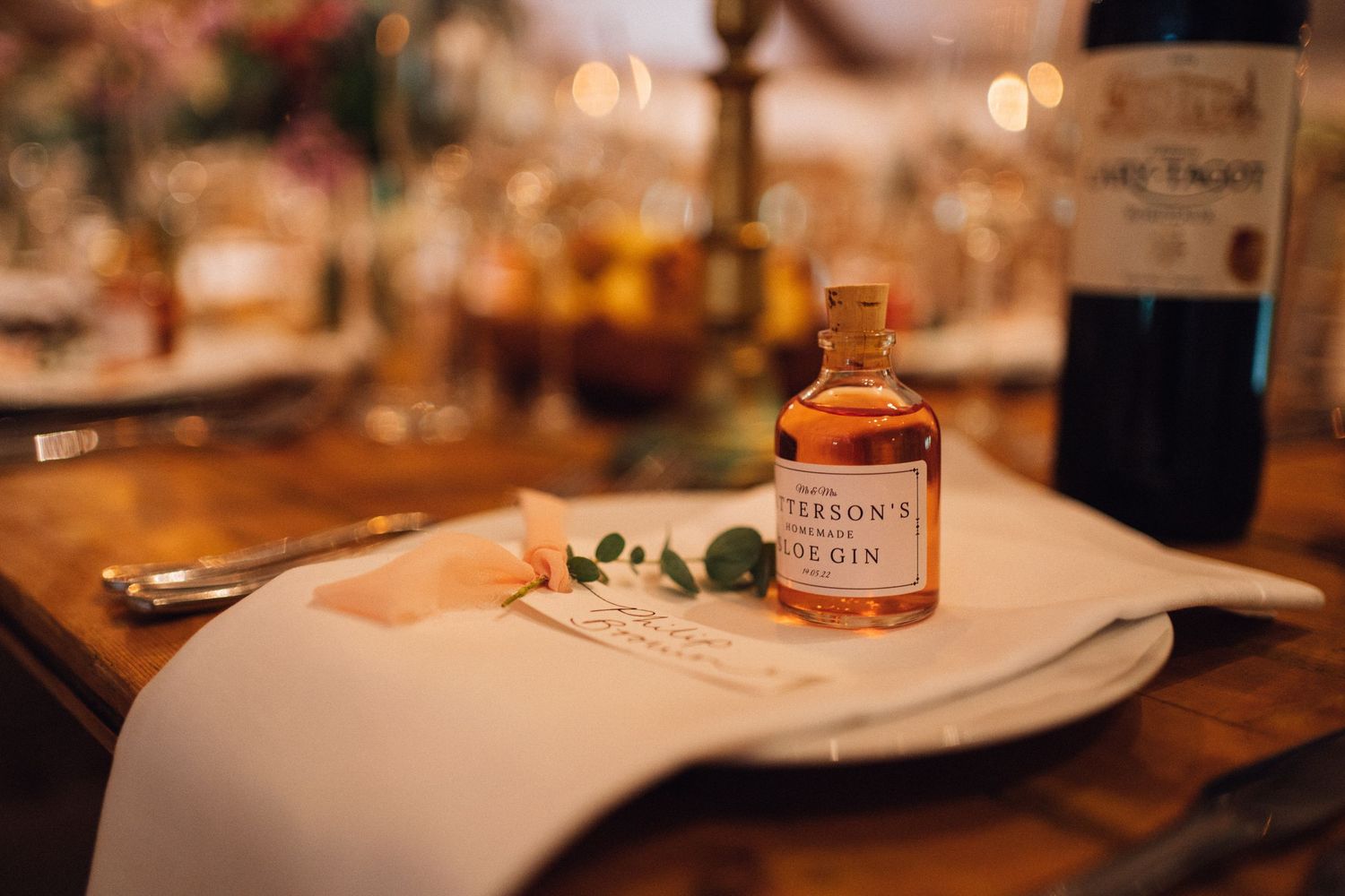 Table settings with wine bottles and place cards at rustic wedding reception.