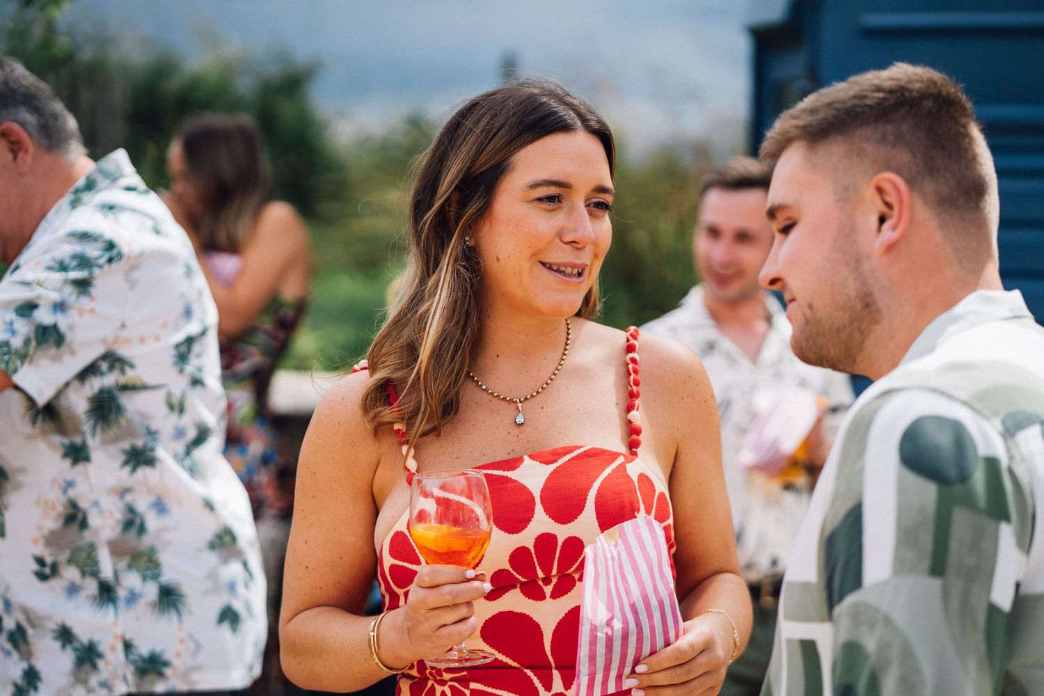 Wedding guests enjoy drinks and conversation during an outdoor summer reception.