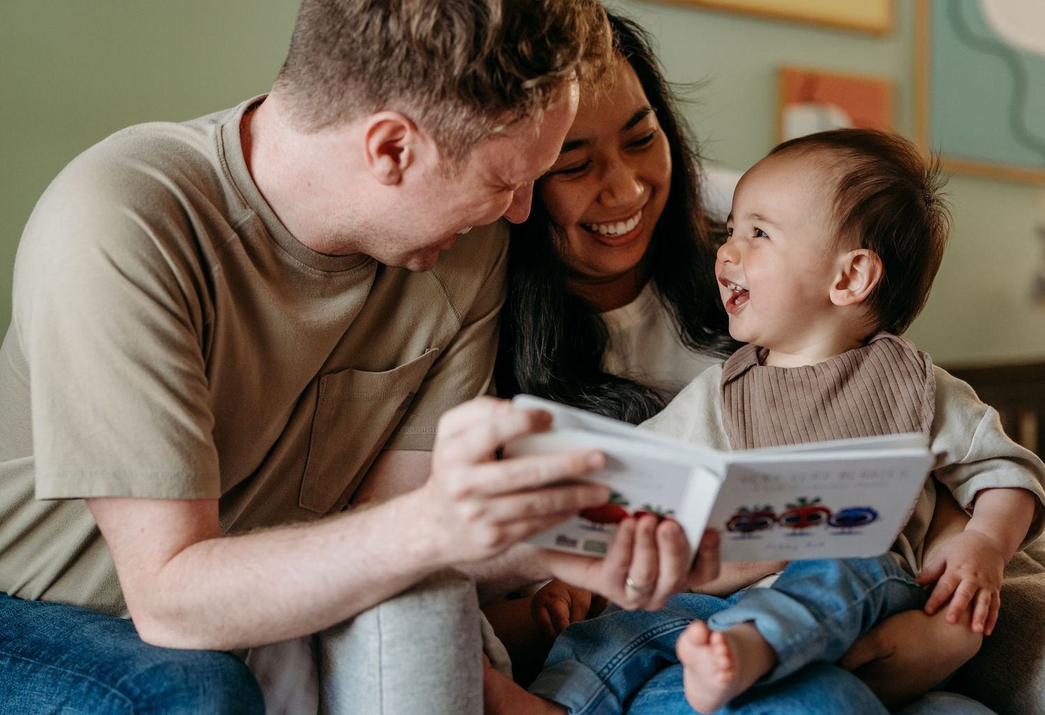 A joyful family moment reading a children's book together on a couch.