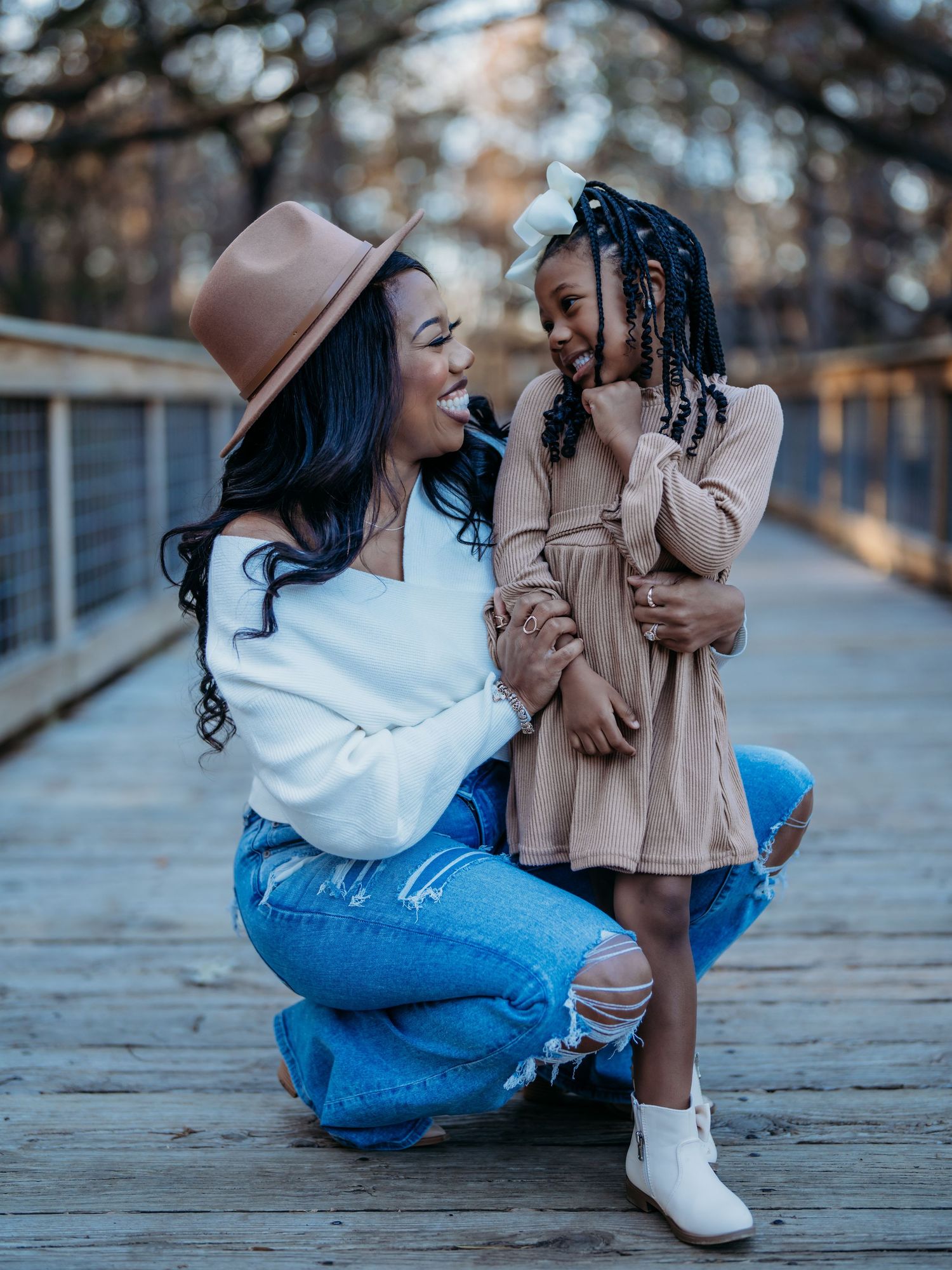 A parent and child share a joyful moment together on a bridge, wearing casual fall outfits in warm autumn lighting.