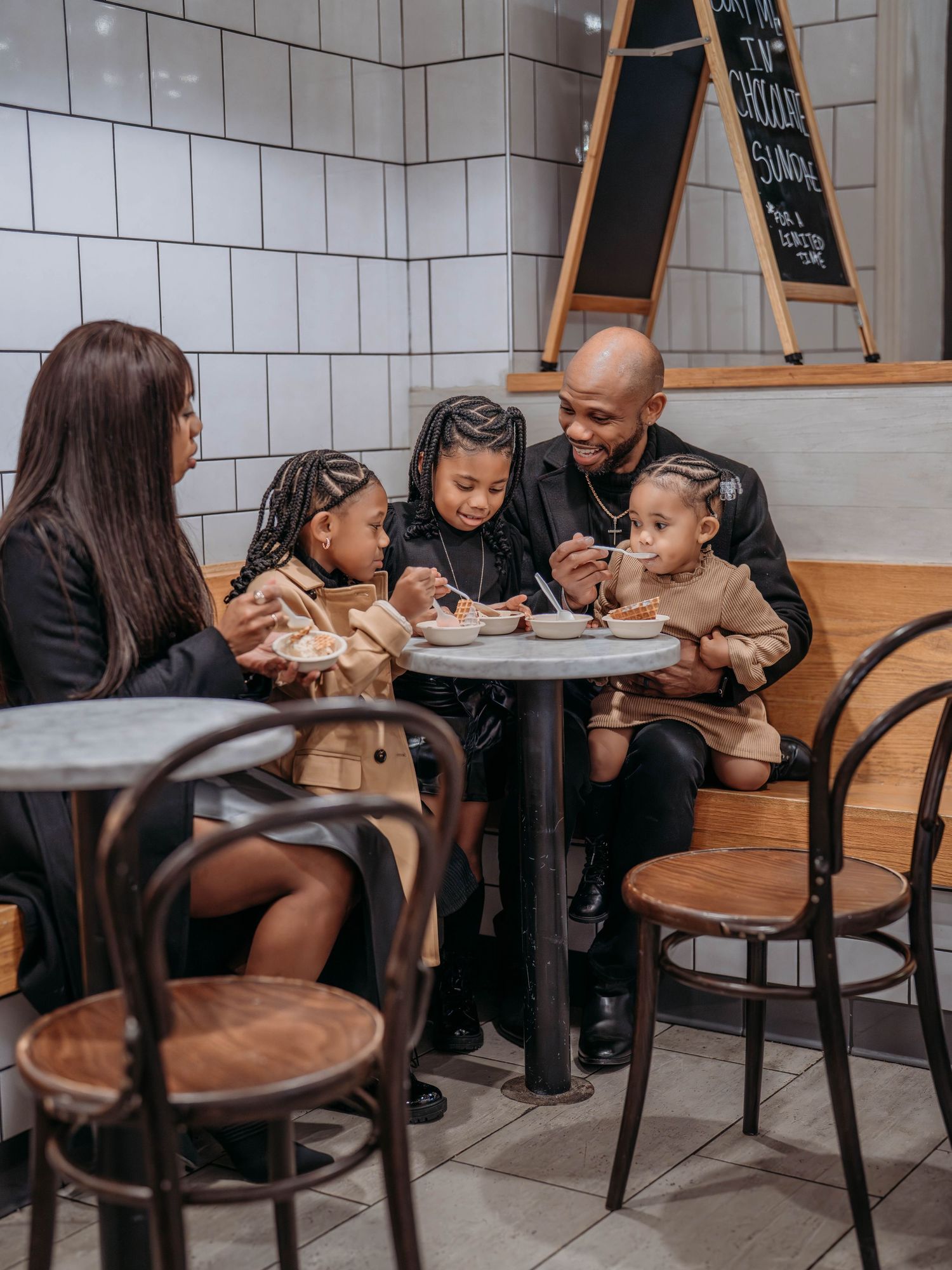 A family sharing a ice cream together at a restaurant table.